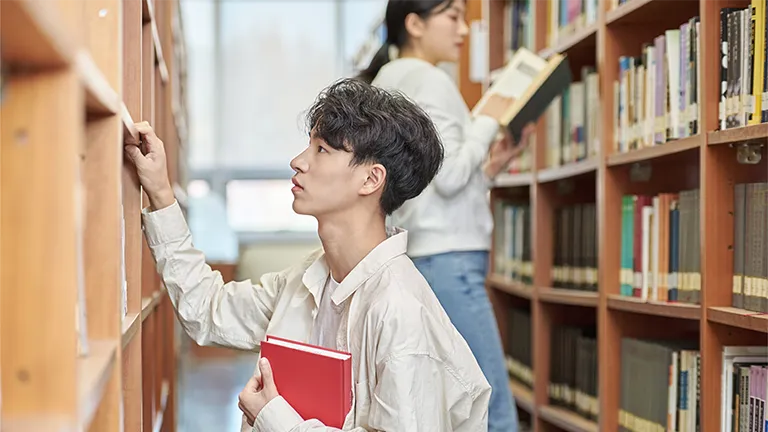 大学図書館で人文科学系の本棚を調べる学生