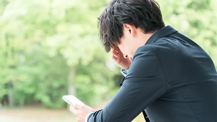 スマートフォンを見て、落ち込んでいる高校生