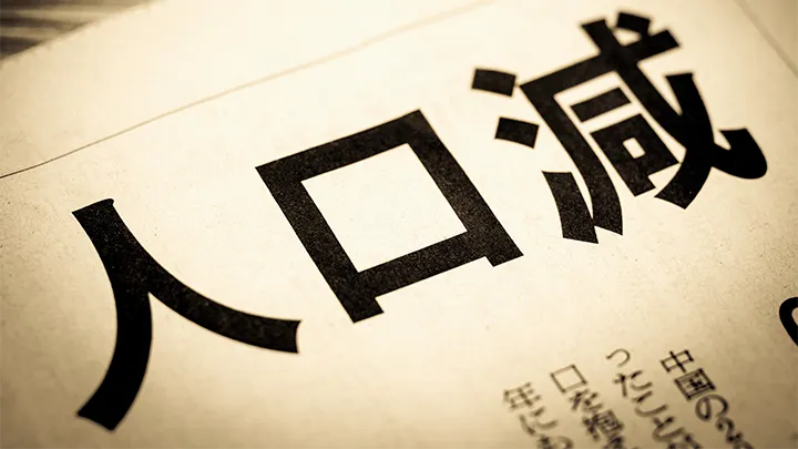 18歳人口の減少問題を報じる新聞の見出し。「人口減」の文字が大きく写されており、大学経営の課題を象徴している。