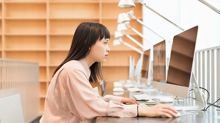 女子大学における教育の現代化を象徴する画像。クリーンで近代的な学習スペースで、女子学生がPCに向かって真剣に学んでおり、情報科学や理系分野への進出を表している。