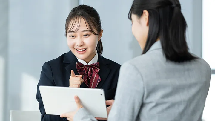 年内入試と一般入試の併願戦略について、タブレットを使いながら相談する高校生と講師